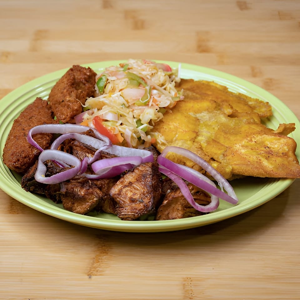 A vegan meal with plantains, fried plant-based protein, and a side salad with red onions.